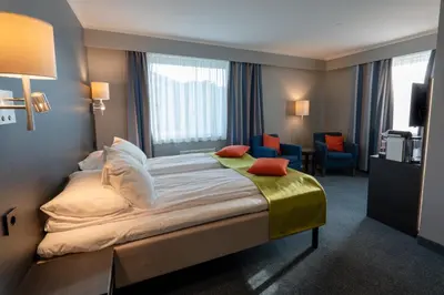a hotel room with a bed and a living room at Thon Hotel Måløy in Måløy