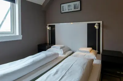 two beds in a room with a large window at Pensjonat Jarlen in Trondheim