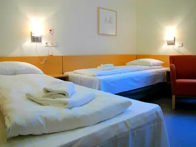 a hotel room with two beds and a chair at Hotel St. Olav in Trondheim
