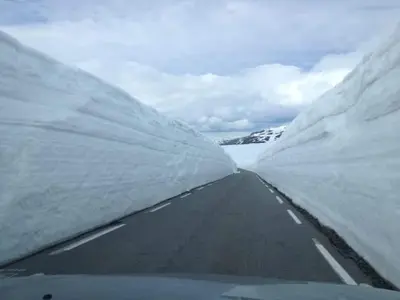 a road between two snow covered mountains at Steinshølen Holiday Home in Flåm