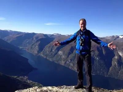 a man standing on top of a mountain with his arms outstretched at Steinshølen Holiday Home in Flåm