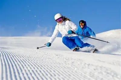 two people are skiing down a snow covered slope at Trysil Hotel in Trysil