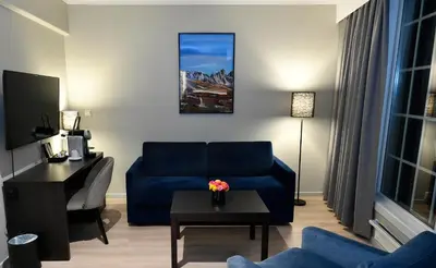 a living room with a blue couch and a table at Thon Hotel Baronen in Ålesund