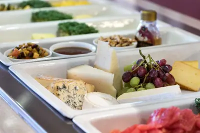 a tray filled with different types of cheese and grapes at Tyrifjord Hotell in Vikersund