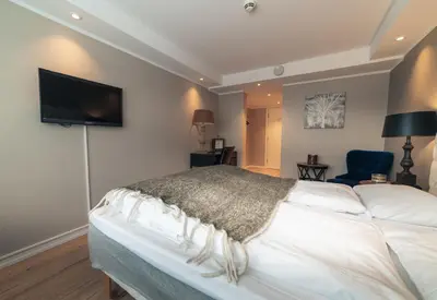 a bedroom with a bed and a tv on the wall at Ustedalen Hotel Geilo in Geilo