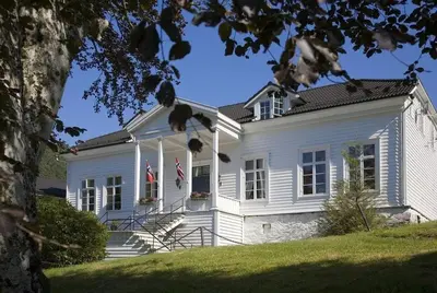 a white house with an american flag on it at Fjordslottet Hotel in Fotlandsvåg