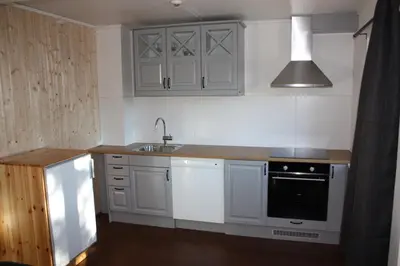 a kitchen with white cabinets and a sink and a stove at Furulund Pensjonat in Ron