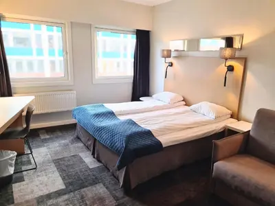 a hotel room with a bed and a chair at City Living Sentrum Hotel in Trondheim