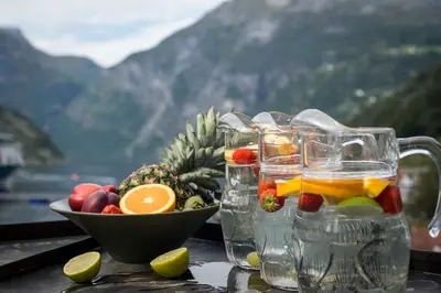 a table with a bowl of fruit and glasses of water at Havila Hotel Geiranger in Geiranger