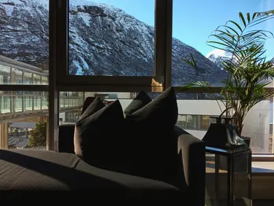 a living room with a couch in front of a window at Havila Hotel Geiranger in Geiranger