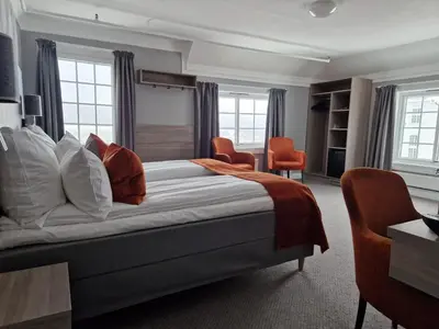 a hotel room with a bed and chairs and windows at Dr. Holms Hotel in Geilo