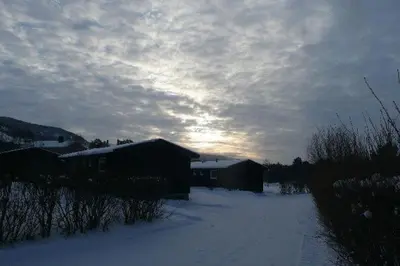 a house in the snow with the sunset in the background at Dovre Motell in Dovre