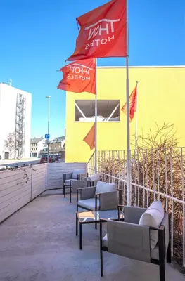 a row of chairs under an umbrella next to a building at Thon Hotel Storgata in Kristiansund