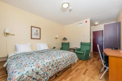 a bedroom with a bed and two chairs and a desk at Frich`s Hotel Surnadal in Surnadal