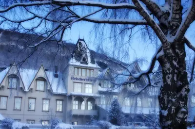 a building covered in snow in front of a tree at Fleischer's Hotel in Vossevangen
