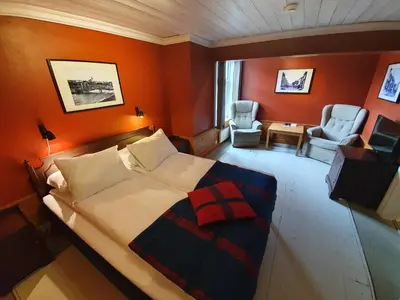 a bedroom with a large bed and two chairs at Vertshuset Røros in Røros
