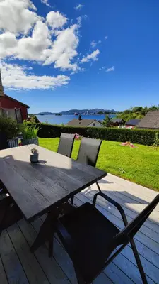 a wooden table and chairs on a deck with a view of the water at Apartment Ulsteinvik in Ulsteinvik