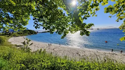 a beach with people playing in the water at Apartment Ulsteinvik in Ulsteinvik