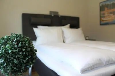 a bed with white sheets and a plant next to it at Støren Hotel in Storen