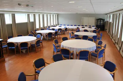a room with white tables and blue chairs at Støren Hotel in Storen