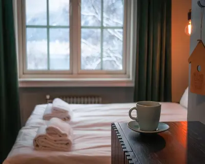 a bed with towels and a cup of coffee on a table at Trolltunga Hotel in Odda