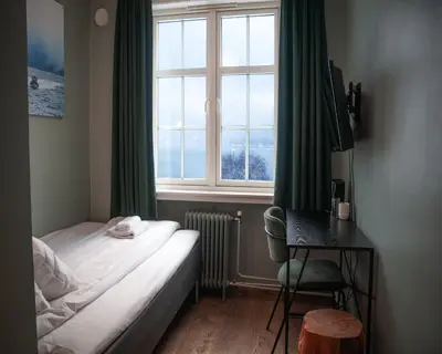 a bedroom with a bed and a desk and a window at Trolltunga Hotel in Odda