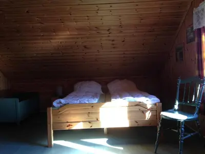 a bed in a wooden room with a chair at Løngdal in Tuddal