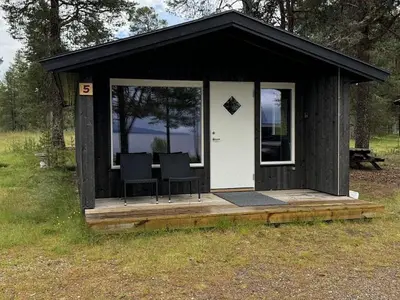 a black and white shed with two chairs in it at Femundtunet in Drevsjø
