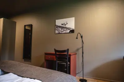 a bedroom with a desk and a chair next to a bed at Trolltun Hotel & Hytter in Dombås
