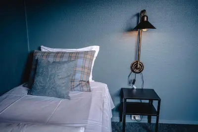 a bed with a pillow and a lamp on a table at Trolltun Hotel & Hytter in Dombås