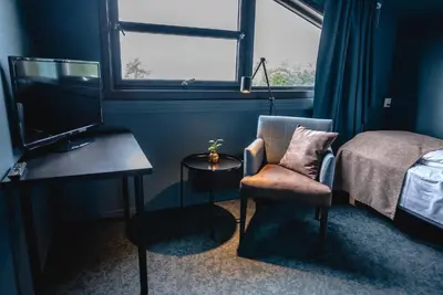 a bedroom with a bed and a chair and a desk at Trolltun Hotel & Hytter in Dombås