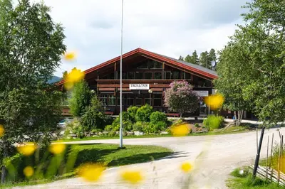 a large wooden building with yellow flowers in front of it at Trolltun Hotel & Hytter in Dombås