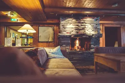 a living room with a couch and a stone fireplace at Gudbrandsgard Hotel in Kvitfjell