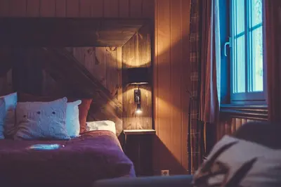 a bedroom with a bed and a lamp and a window at Gudbrandsgard Hotel in Kvitfjell