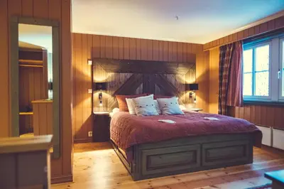 a bedroom with a large bed with a red comforter at Gudbrandsgard Hotel in Kvitfjell