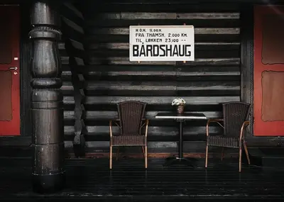 two chairs and a table with a sign on a wall at Bårdshaug Herregård in Orkanger
