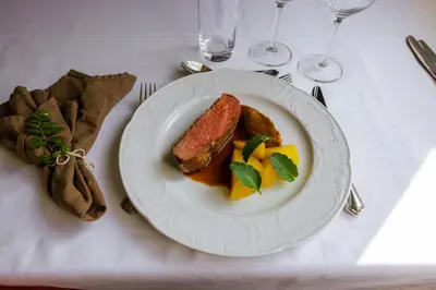 a plate of food with meat and vegetables on a table at Røisheim Hotel & Skysstasjon in Lom