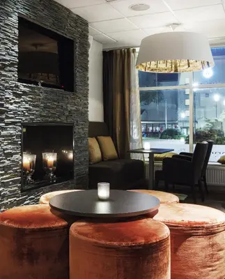 a living room with a table and a fireplace at Quality Hotel Grand Kristiansund in Kristiansund