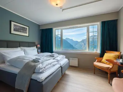 a bedroom with a bed and a large window at Hotel Utsikten - by Classic Norway Hotels in Geiranger