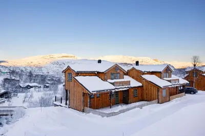 a large wooden house in the snow with snow at Filefjellstuene hytter og leiligheter in Tyinkrysset
