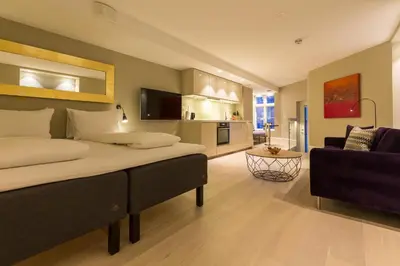 a bedroom with a large bed and a living room at 2 Døtre Apartments by Hotel Park in Bergen