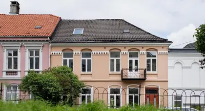 a large pink building with a balcony on it at 2 Døtre Apartments by Hotel Park in Bergen