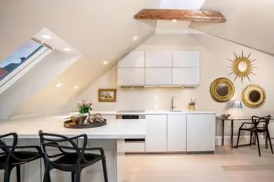 a kitchen with white cabinets and black chairs at 2 Døtre Apartments by Hotel Park in Bergen