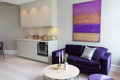 a living room with a purple couch and a kitchen at 2 Døtre Apartments by Hotel Park in Bergen