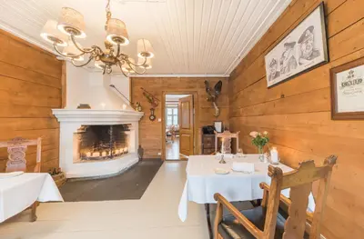 a dining room with a table and a fireplace at Gloppen Hotell - by Classic Norway Hotels in Sandane