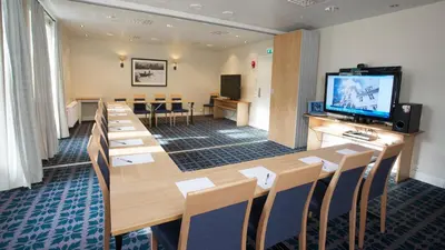 a conference room with tables and chairs and a flat screen tv at Gloppen Hotell - by Classic Norway Hotels in Sandane