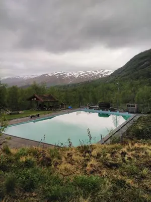 a large swimming pool with mountains in the background at Voss Mountain Lodge in Mjølfjell