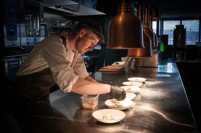 a chef preparing food on a counter in a restaurant at Bergstadens Hotel & Spa in Røros
