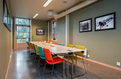 a conference room with a long table and colorful chairs at Thon Hotel Bjørneparken in Flå