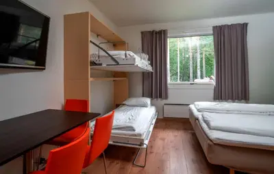a small room with a bed and a table and chairs at Thon Hotel Bjørneparken in Flå